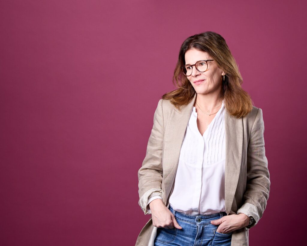 Frau in blasser Jacke vor Hintergrund